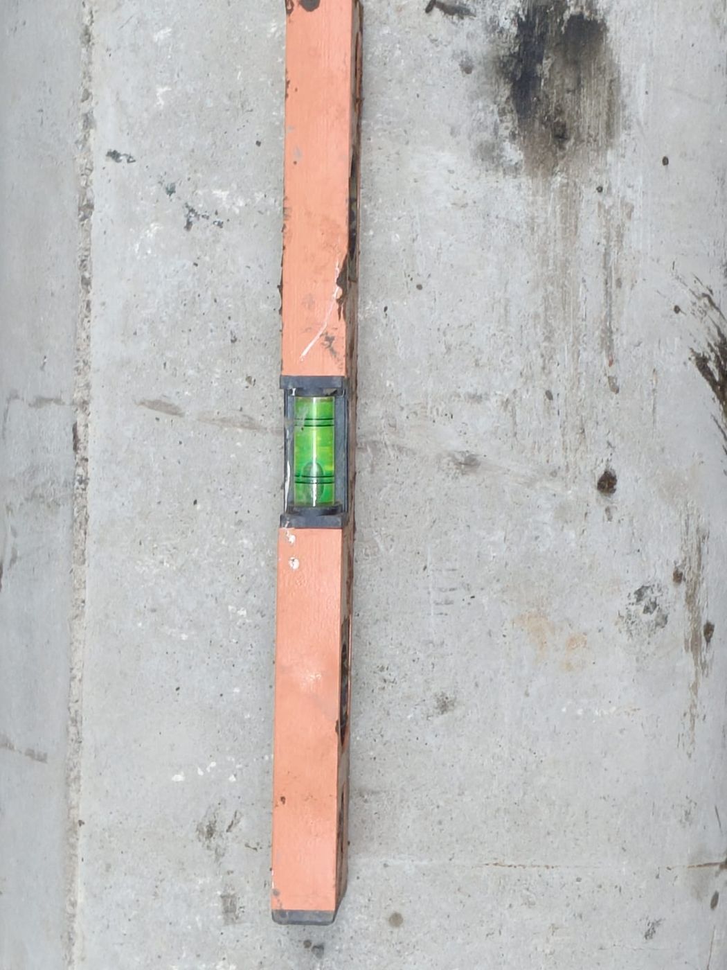 Spirit level placed on a laid drainage pipe to verify its slope
