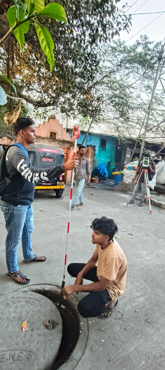 Survey team recording an existing manhole level